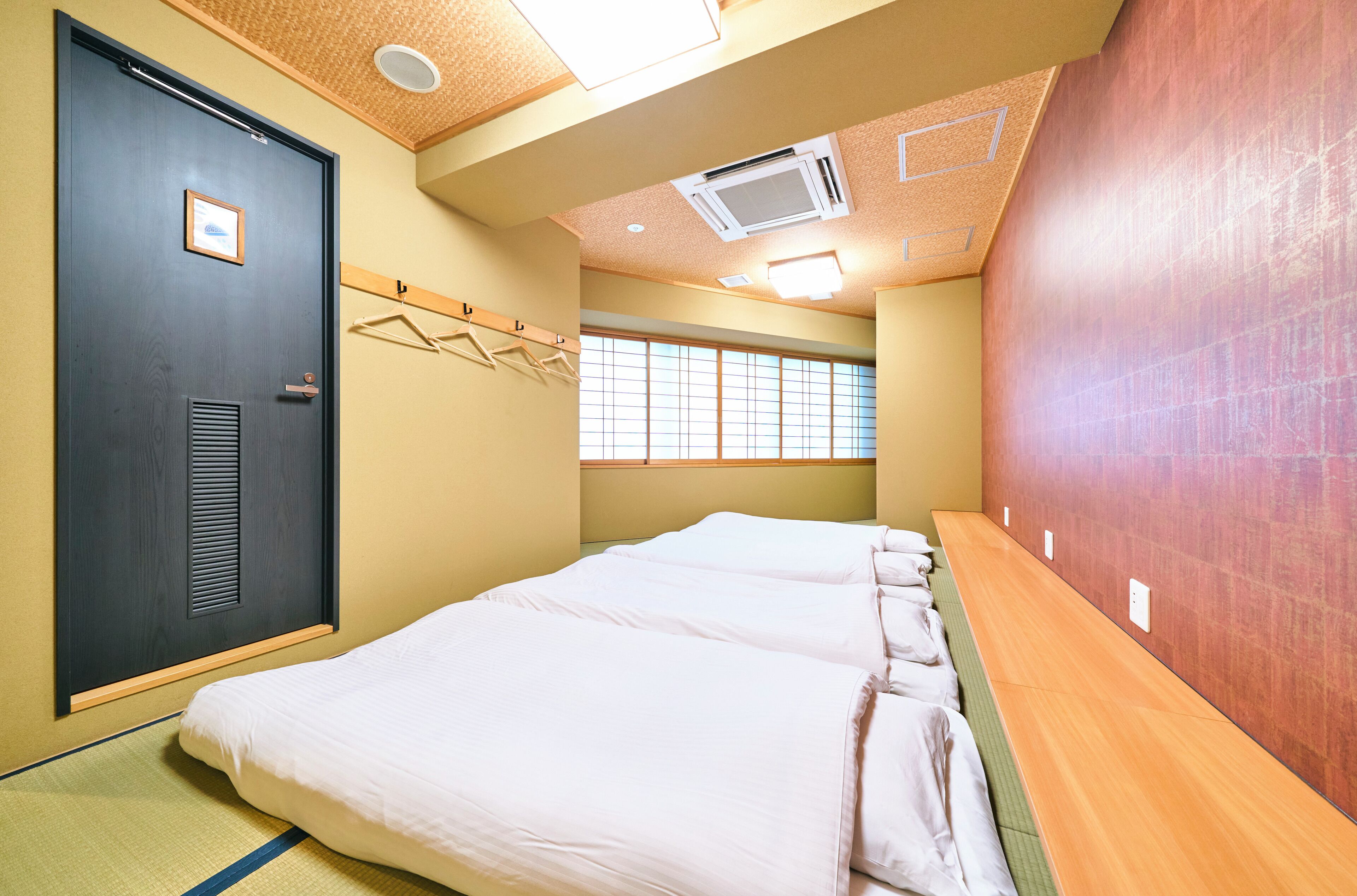A hotel room with a bed, a door, a window, and a wall-mounted towel rack.