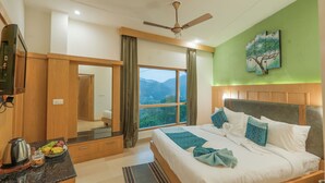A hotel room with a bed, a TV, a window with curtains, and a painting on the wall. - Excel Hotels & Resorts Bhimtal (Nainital)