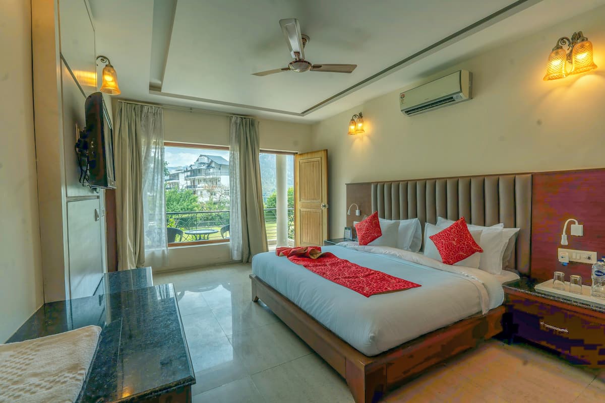 A hotel room with a large bed, a desk, a ceiling fan, and a view of the outdoors.