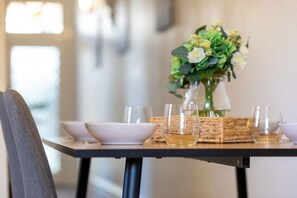 A dining table set with white plates, bowls, and glasses, accompanied by a vase of flowers.