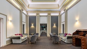 A luxurious hallway with a high ceiling, ornate columns, and a grand desk. - Elegance and heritage stay - CBD (Melbourne)