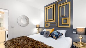 A modern bedroom with a large bed, decorative wall panels, a round mirror, and a fur throw. - Elegance and heritage stay - CBD (Melbourne)