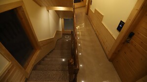 A wooden interior with a polished staircase, a door with a number display, and a small window. - Golden Wood Manali By Rosetum (Manali)
