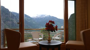 A room with a table and chairs facing a mountain view. - Golden Wood Manali By Rosetum (Manali)