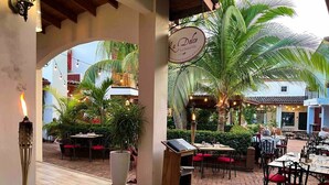 Area esterna con tavoli e sedie, un cartello con la scritta 'La Dolce' e una scala che conduce a un piano superiore.