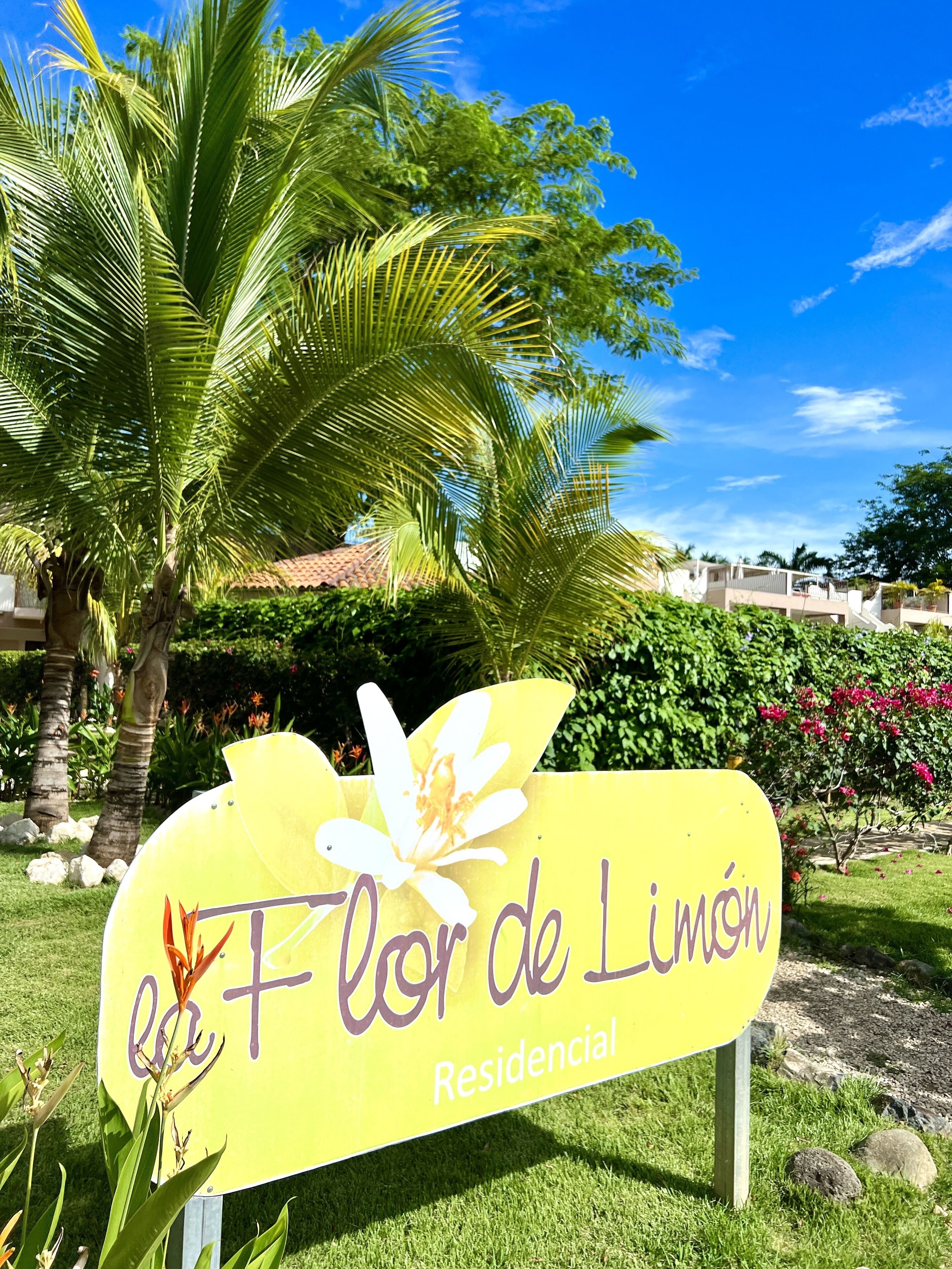 A yellow sign with a white flower and text reading "la Flor de Limón Residential".