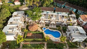 Vista aerea di un resort con diversi edifici, una piscina e una vegetazione lussureggiante.