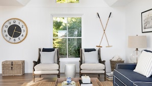 A living room with two armchairs, a sofa, a coffee table, a clock, a window, and a lamp.