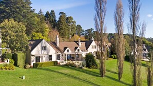A large, modern house with a well-maintained lawn and mature trees.