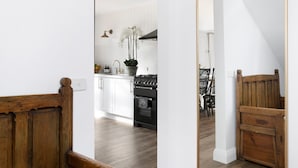 A kitchen with white cabinets, a black stove, and a wooden bench.