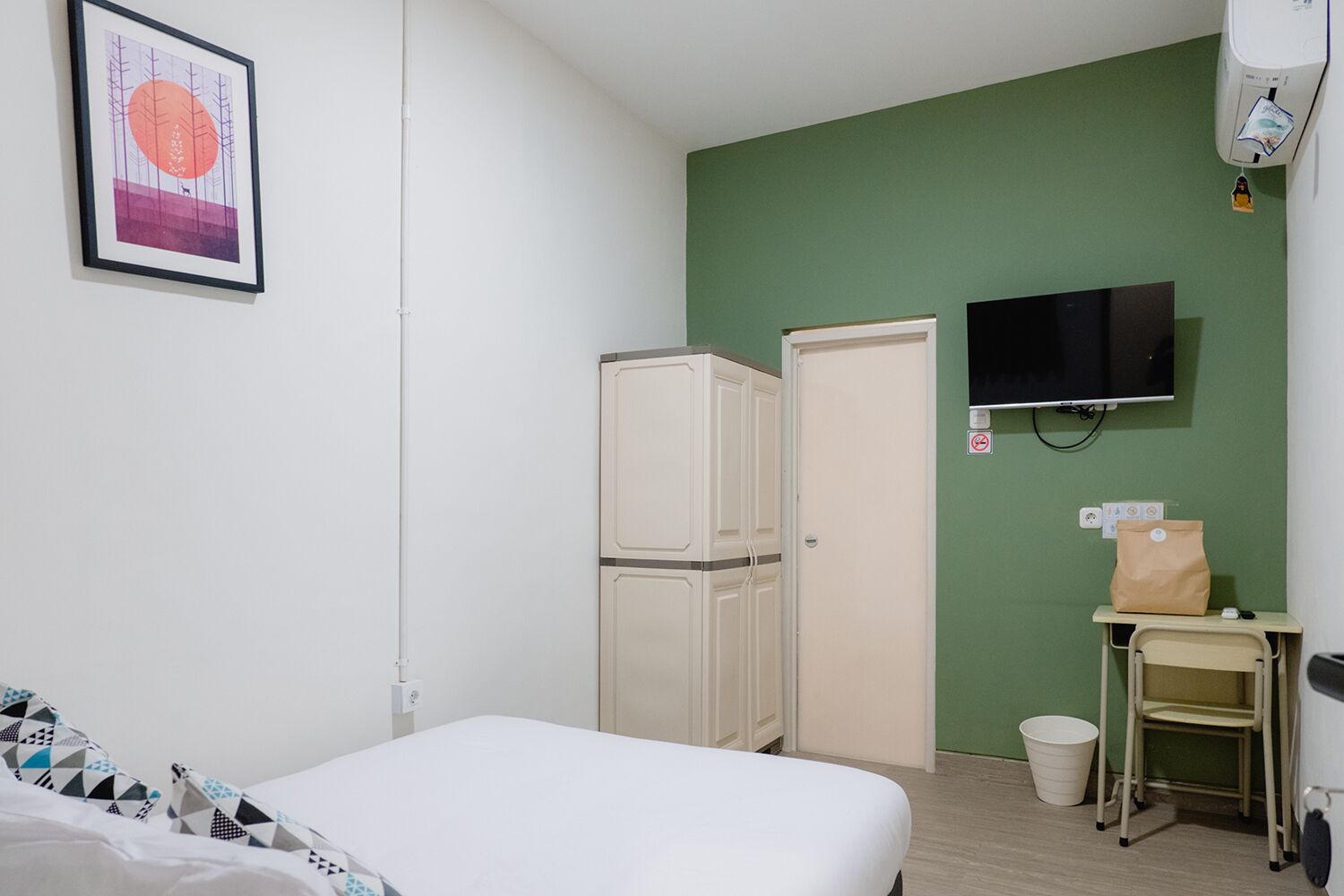 Une chambre d’hôtel équipée d’un lit, d’un réfrigérateur, d’une télévision et d’un petit bureau avec une chaise.