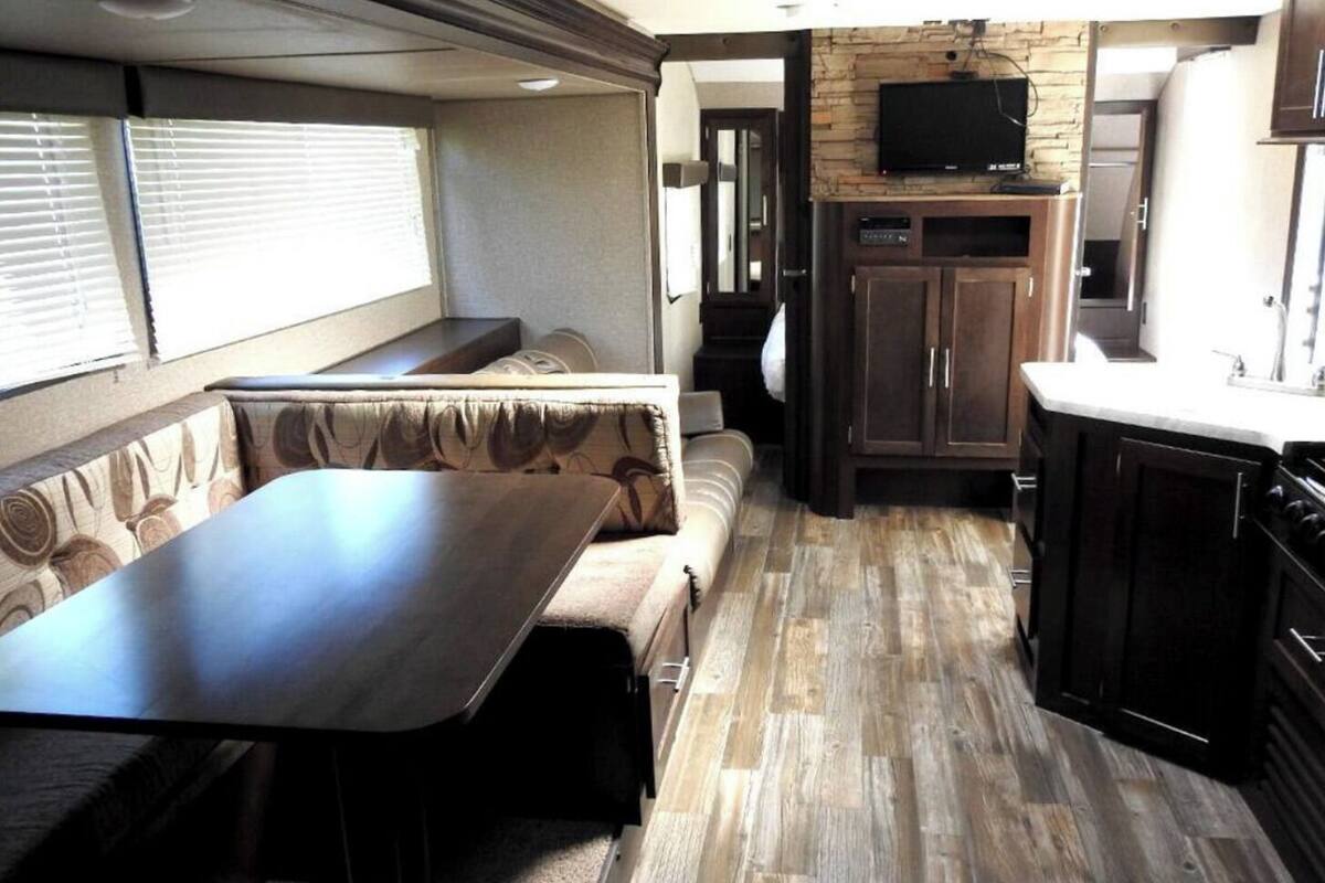 Interior compacto de una caravana con comedor, asientos y una kitchenette.