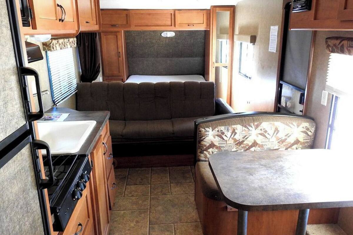 Interior compacto de una caravana con kitchenette, zona de comedor y litera.