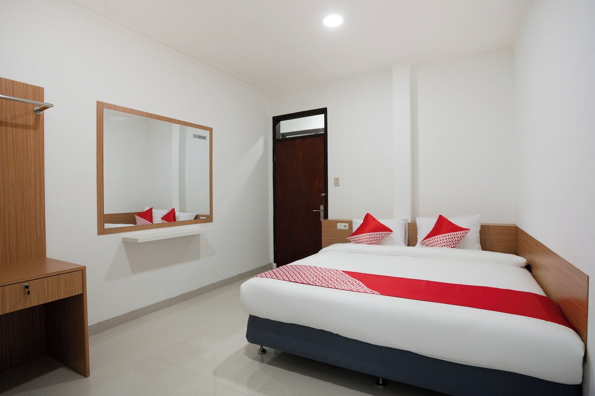 Ein Hotelzimmer mit einem Bett, einem Holztisch, einem Spiegel und einer Tür.