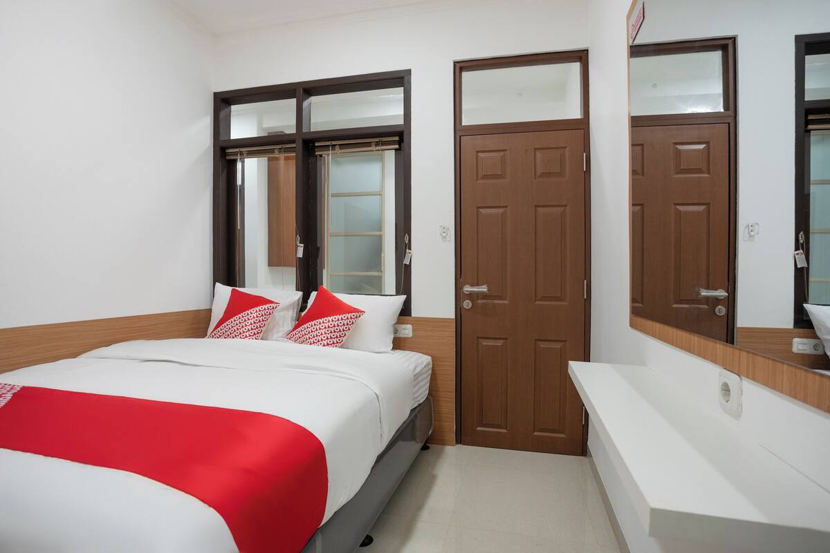 Une chambre d’hôtel avec un lit, une porte en bois et un meuble-lavabo dans la salle de bain.