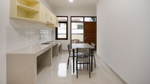 Une cuisine dotée d’un évier encastré, d’une table à manger avec des chaises et d’une porte en bois.