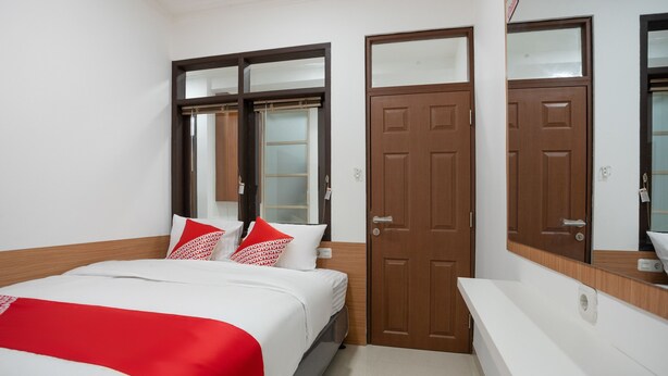 Une chambre d’hôtel avec un lit, une porte en bois et un meuble-lavabo dans la salle de bain.
