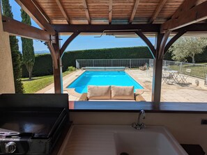 A view from a covered outdoor area to a swimming pool with a patio and outdoor furniture. - Large House With Private Pool and Valley View (Savigny-sur-Grosne)