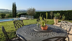 A round metal table with chairs, a potted cactus, and a view of a swimming pool and landscape. - Large House with Private Pool and Valley View (Savigny-sur-Grosne)