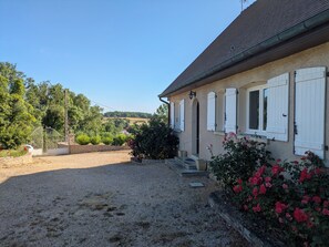 A house with a gravel driveway, a wooden gate, and a garden with roses. - Large House With Private Pool and Valley View (Savigny-sur-Grosne)