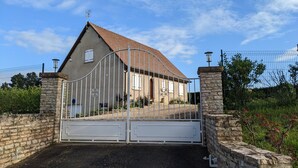 A gated property with a stone wall and metal gate, a house with a tiled roof, and a clear blue sky. - Large House with Private Pool and Valley View (Savigny-sur-Grosne)