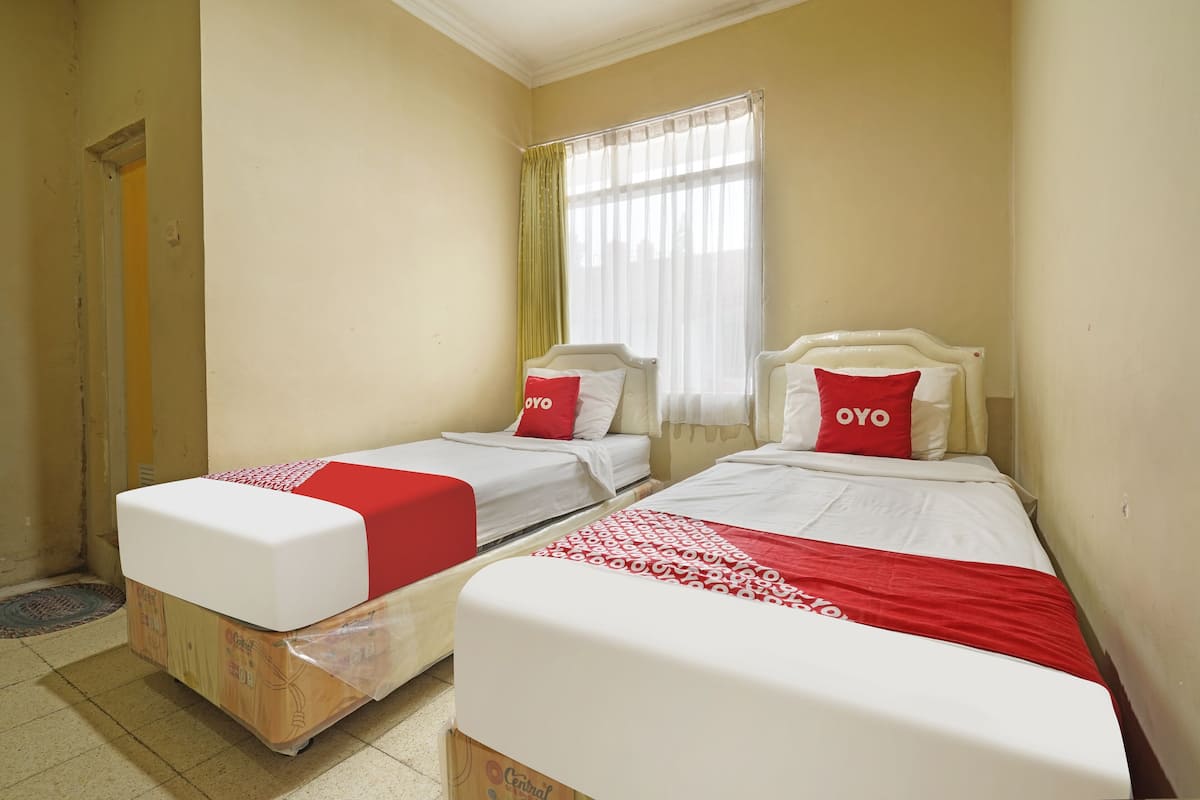 Ein Zimmer mit zwei Betten, jeweils mit weißer Matratze und roter Bettwäsche.