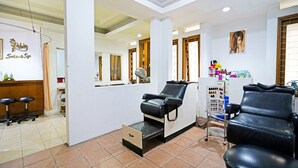 Ein Salon-Innenraum mit zwei schwarzen Ledersesseln, einem Spiegel und einer Theke. Auf ihr steht ein Schild mit der Aufschrift 'Polina Salon & Spa'.