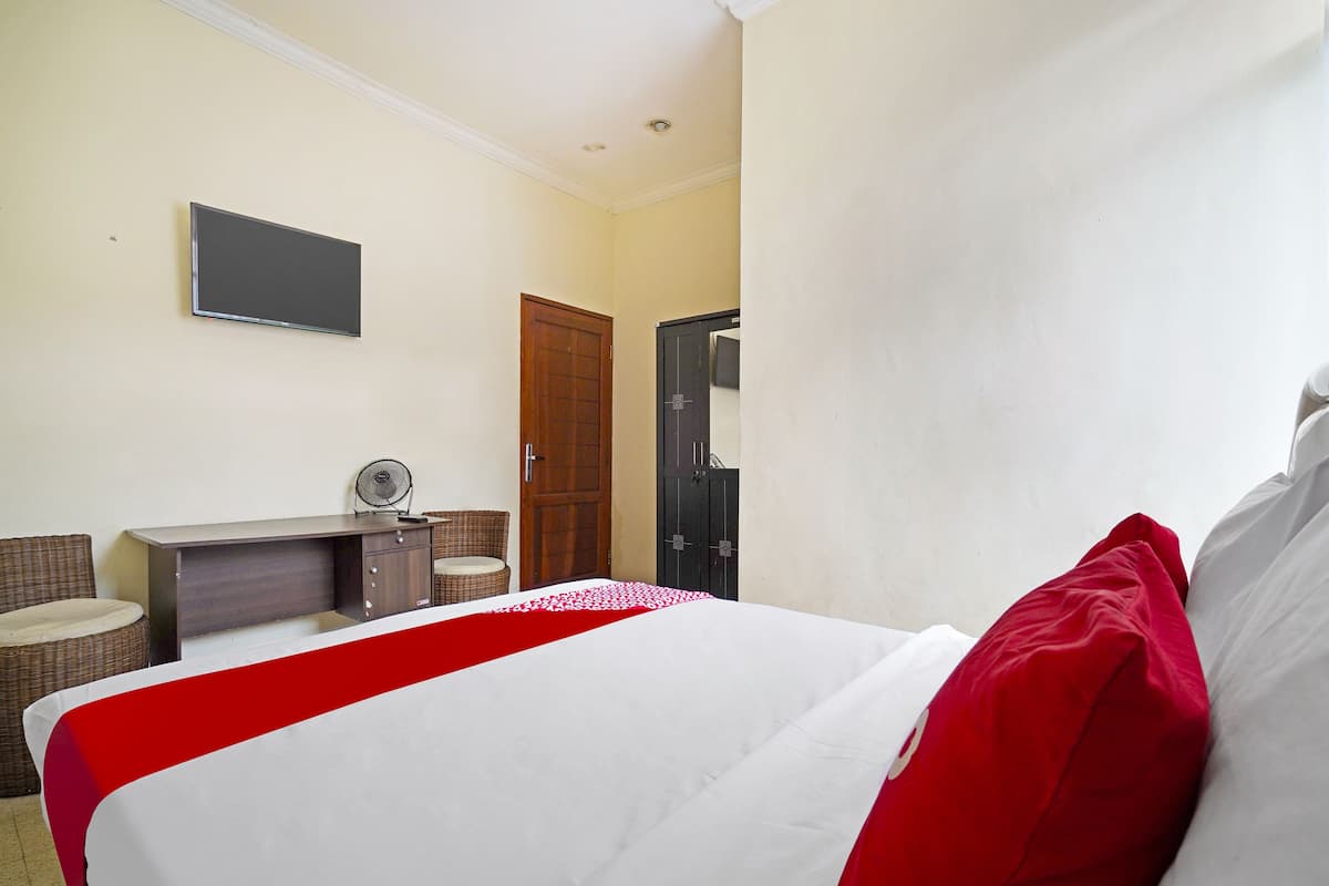 Ein Hotelzimmer mit Bett, Schreibtisch, Stuhl, Kleiderschrank und Fernseher an der Wand.