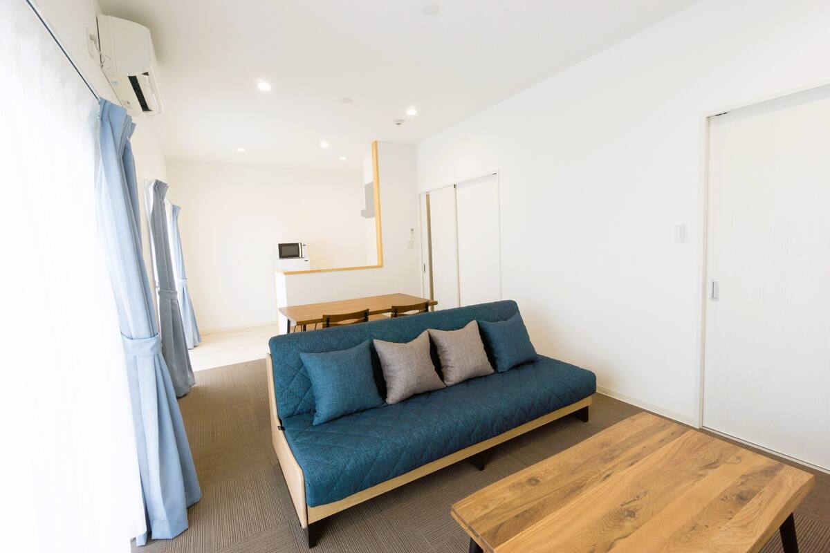 Una habitación moderna con un sofá azul, una mesa de madera y una cama.