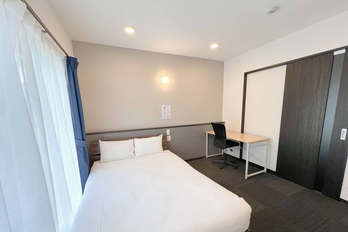 Una habitación de hotel con una cama grande, un escritorio y un armario.