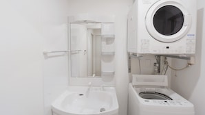 Une petite salle de bain avec un lavabo sur colonne, un miroir et un lave-linge fixé au mur.