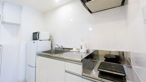 Une cuisine moderne avec des armoires blanches, un plan de travail en acier inoxydable, un four à micro-ondes encastré, une bouilloire et une cuisinière.