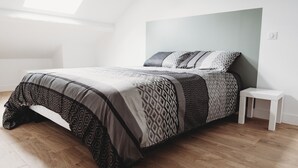 Une chambre à coucher moderne avec une lucarne, une couvre-lit à motifs et une petite table de chevet.