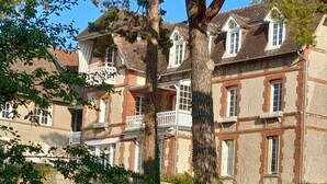 Un immeuble à plusieurs étages, doté d’une façade en briques, de cadres de fenêtres blancs et d’un balcon.