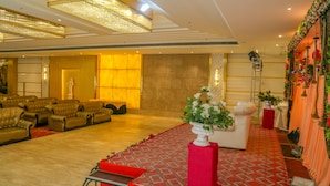 A spacious hall with leather sofas arranged in rows, a central stage, and a decorative wall with plants. - Four Leaf Hotel (Budaun)