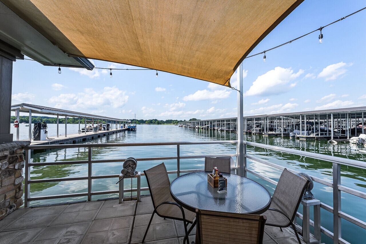 A covered outdoor seating area with a view of a marina and boats.