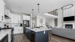 A modern kitchen with white cabinets, a central island, stainless steel appliances, and pendant lighting. - Beautiful Lake Home Retreat with Lake and Marina Access and Golf Cart (Winchester)