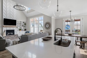 A modern kitchen with a central island, a built-in oven, and a dining area with a bench.