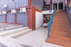 Un bâtiment doté d’un escalier menant à un balcon, de climatiseurs fixés au mur et d’un sol carrelé.