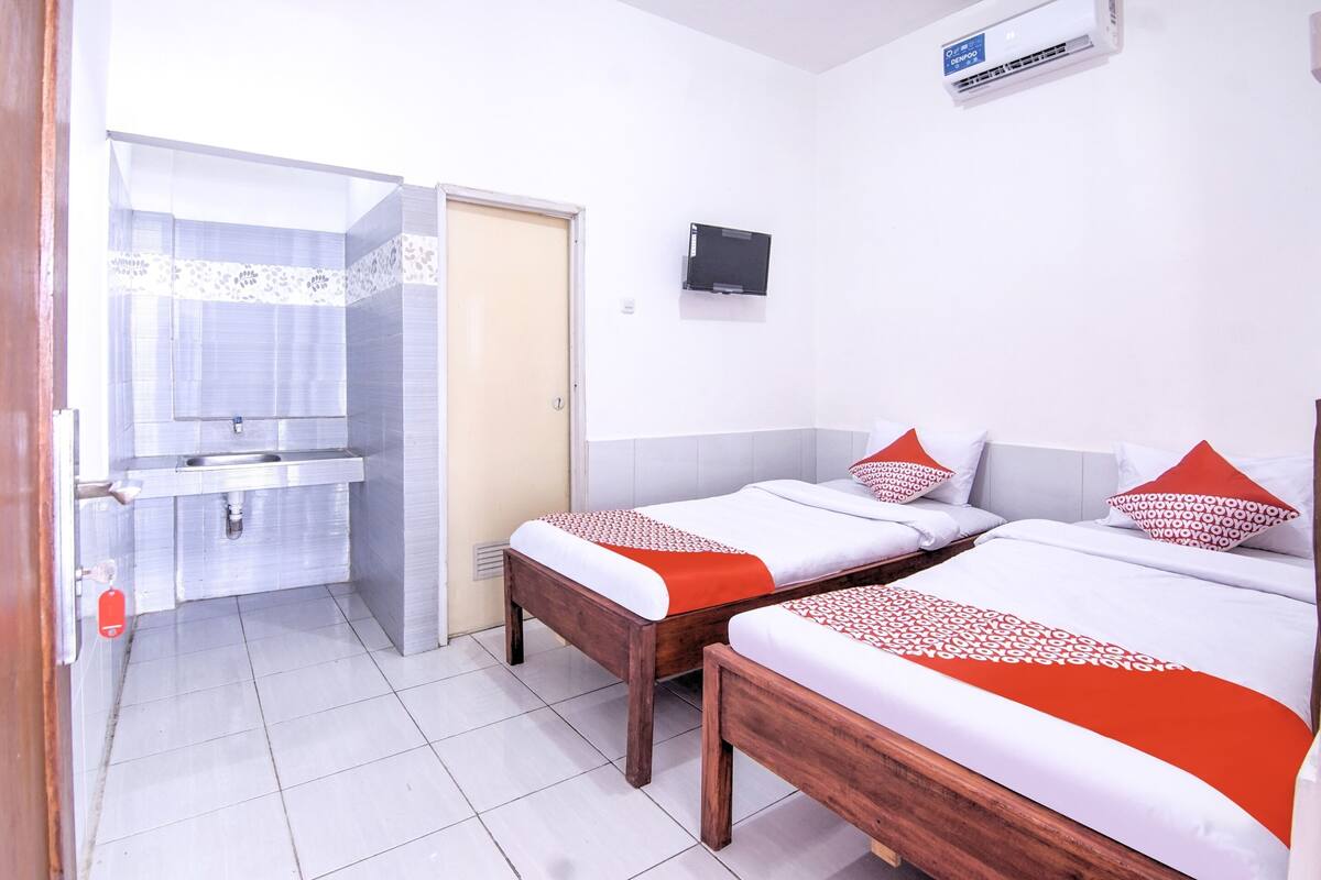 Une chambre d’hôtel avec deux lits, une salle de bain et un téléviseur.