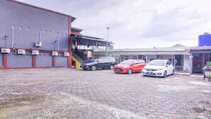 Een parkeerplaats met drie auto's, een gebouw met airconditioners en een trap naar een overdekt gebied.