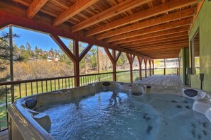 A hot tub under a wooden deck with a view of a residential area.