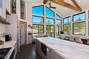 A spacious kitchen with a large island, built-in appliances, and a view of the outdoors through large windows.