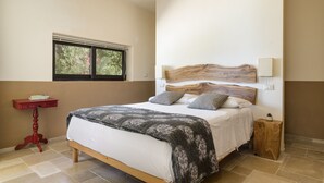 A bedroom with a bed, a window, a red side table, and a wooden nightstand. - Villa Opale by Wonderful Italy (Carovigno)