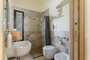 Villa | Badkamer | Een douche, een haardroger, een bidet, handdoeken