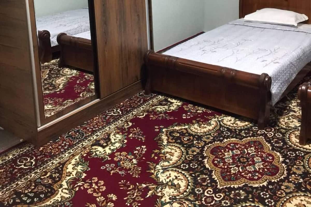A bedroom with a wooden bed, a large mirror, and a patterned carpet.