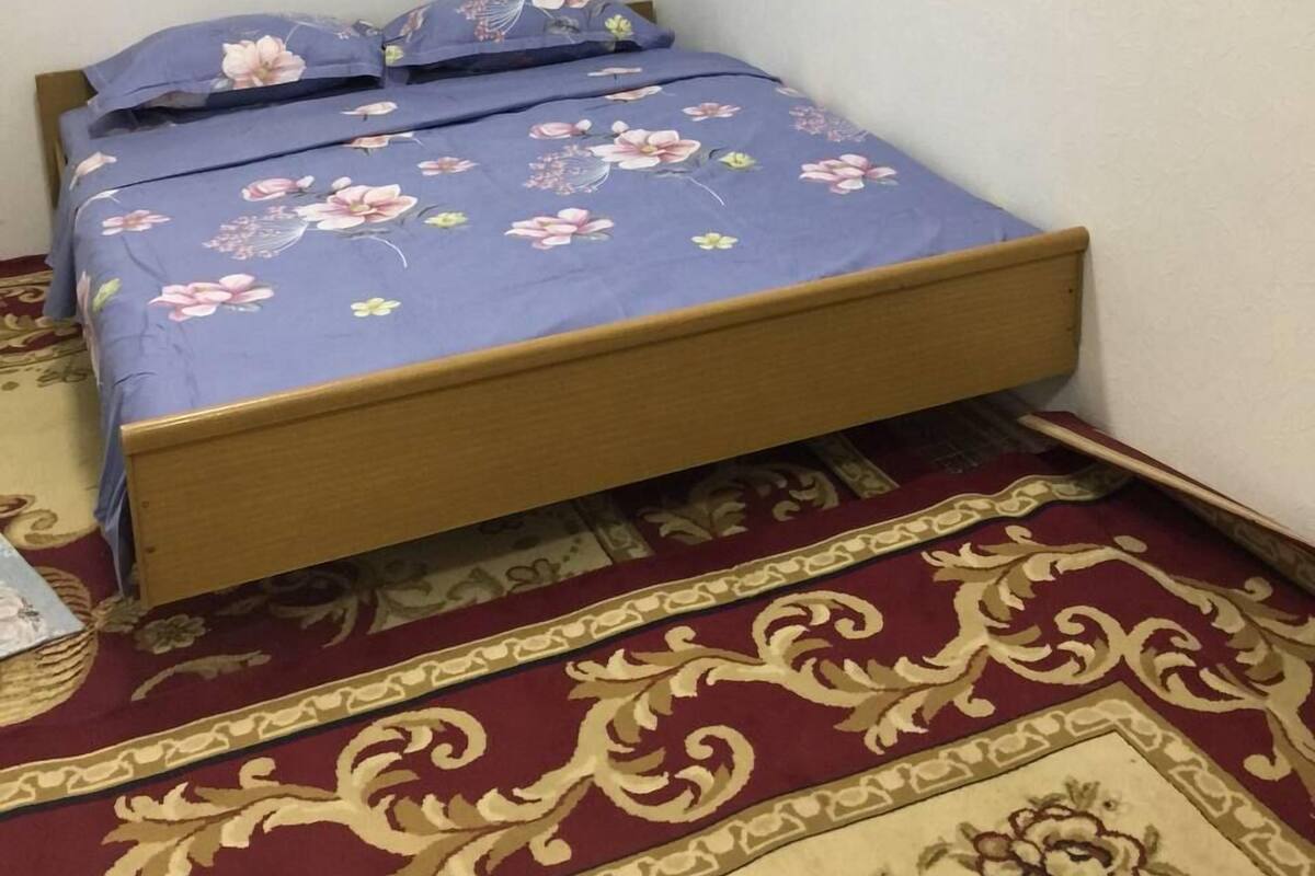 A small, single-bed room with a floral bedspread and a patterned carpet.