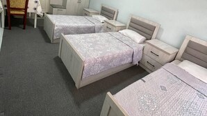 A bedroom with two single beds, a desk, a chair, and a wardrobe.