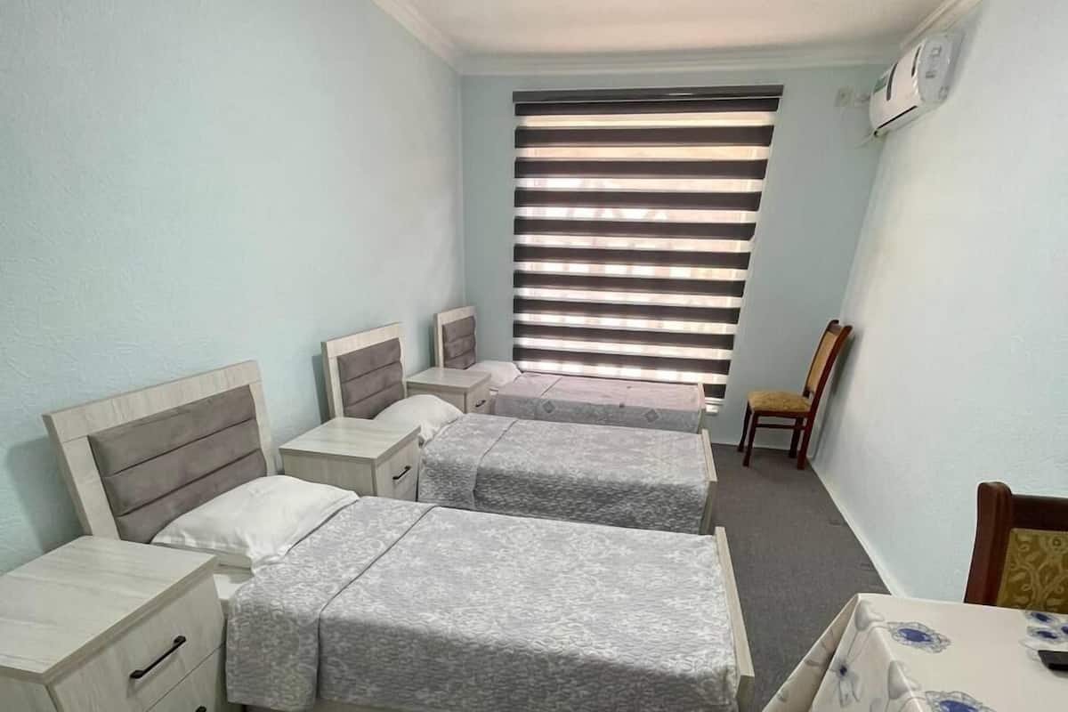 A bedroom with two beds, a desk, a chair, and a window with blinds.