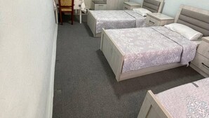 A bedroom with two beds, a chair, a desk, and a wardrobe.